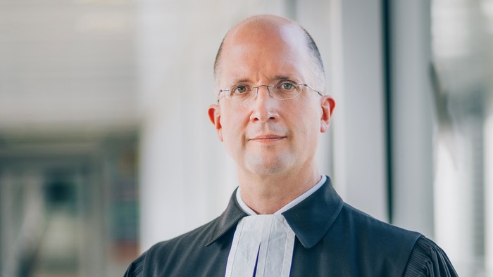 Ein Richter steht vor einem Gebäude.