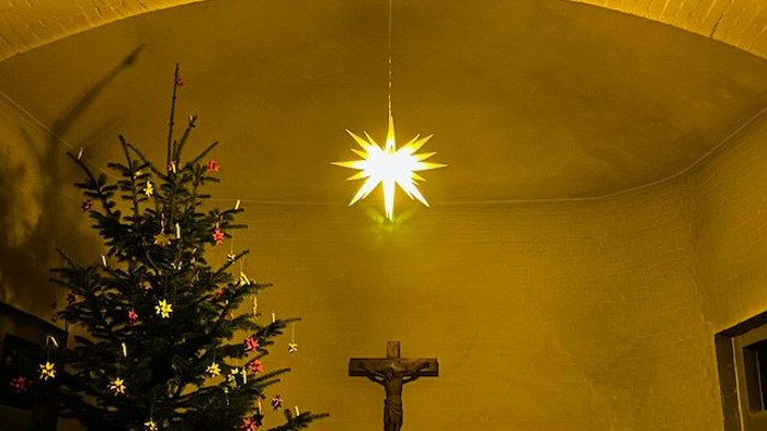 Weihnachtsbaum und Kreuz unter Sternenleuchte