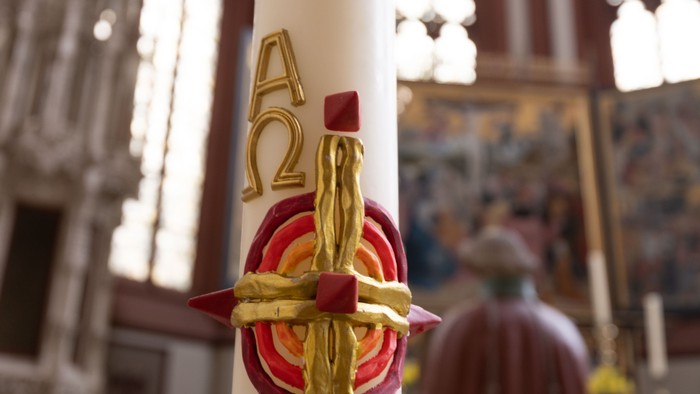 Eine weiße Kerze mit goldenen und roten Verzierungen, die die Buchstaben „A2“ trägt.