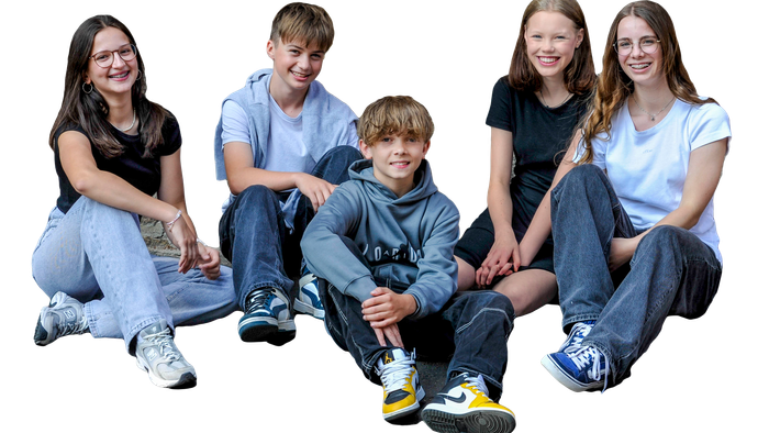 Fünf Jugendliche sitzen im Halbkreis und lächeln