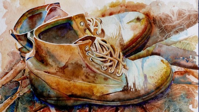 Ein Paar abgetragene, braune Schuhe mit weißen Schnürsenkeln auf einer strukturierten Oberfläche.