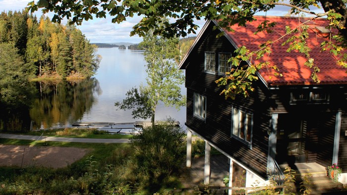 Haus am See mit rotem Dach und Treppe.