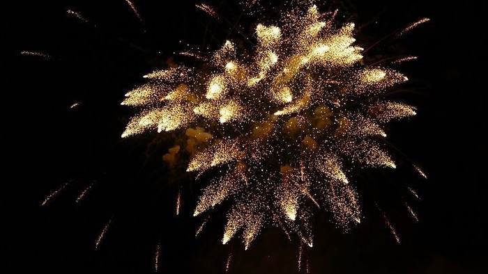 En fyrværkeribomb udløser en stjerneformet udbrud af guldfarvede lys i natten