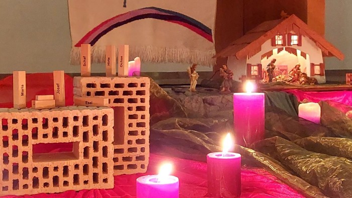 Ein adventlicher Tischschmuck mit Kerzen, Krippe und selbstgebasteltem Krippenstall.