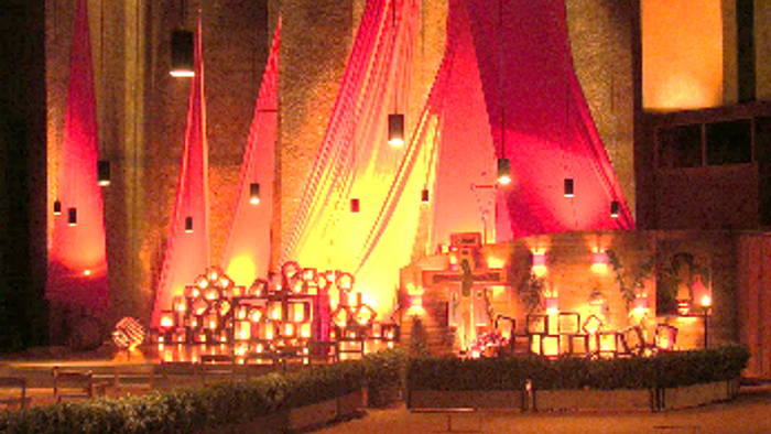 Ein beleuchtetes Zelt mit roten Vorhängen und vielen Laternen im Innenraum.