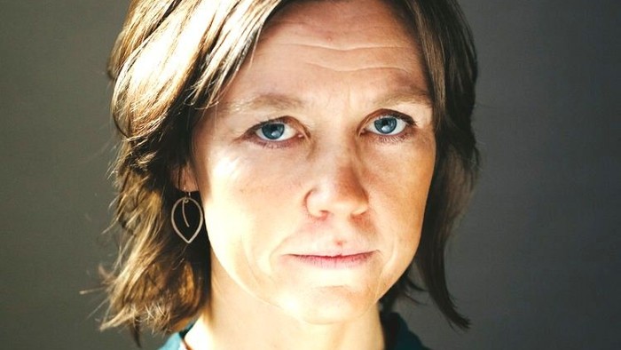 En kvinde med kort, mørkt hår og blå øjne, der bærer en blå og hvid trøje.