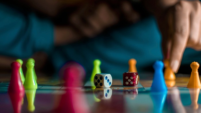 Bunte Spielzeugfiguren und Würfel auf einer blauen Oberfläche