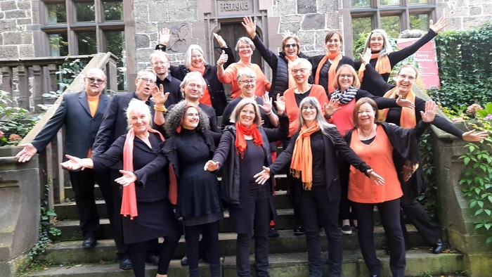 Gruppe von Menschen, die gemeinsam im Freien posieren, einige tragen orangefarbene Schals.