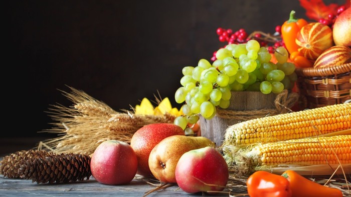 Assorted fruits and vegetables including apples, pears, grapes, corn, and tomatoes displayed together