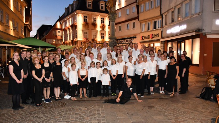 Eine Gruppe von Menschen posiert vor einem Gebäude in einer Stadt.