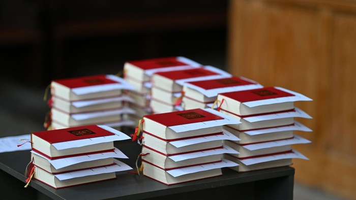 Aufgestapelte gebundene Bücher mit roten Einbänden und gelben Lesebändern, die im Freien ausgestellt sind.