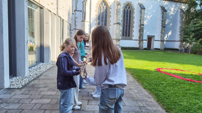 Kinder spielen mit Smartphone vor Kirche