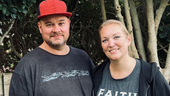 En mand med rød kappe og en kvinde står sammen ved træer