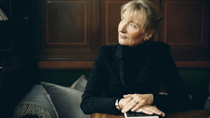 En kvinde sidder på en stol og holder en bog i hendes hænder.