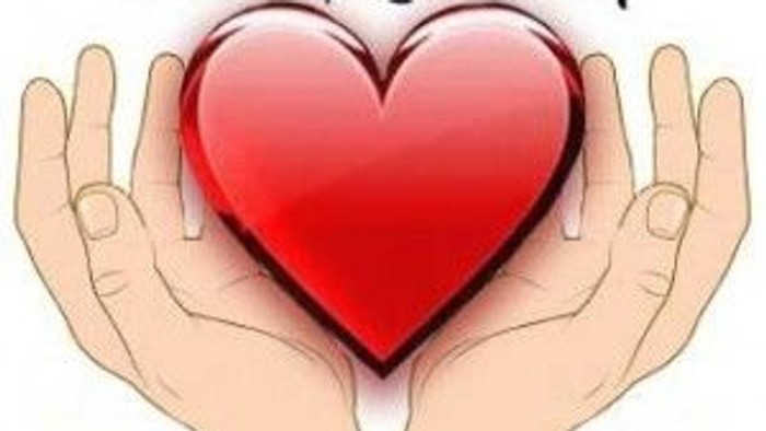Hands gently holding a red heart, with