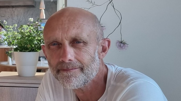 Mand med skæg sidder ved bordet med glas.