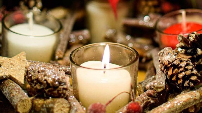 Kerzen, umgeben von Tannenzapfen und Dekorationsgegenständen.