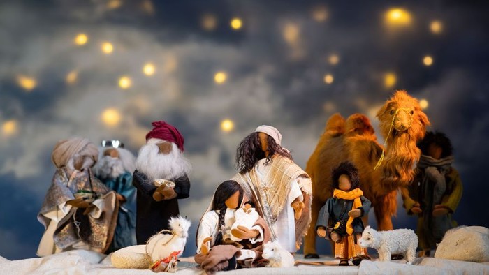 Weihnachtskrippe mit Figuren und Tieren unter sternenklarem Himmel.