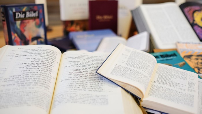 Mehrere aufgeschlagene Bücher liegen auf einem Tisch