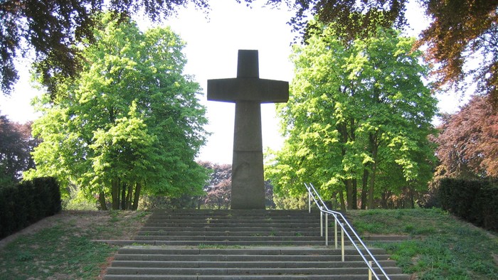 Ein großes Kreuz steht auf einer Treppe in einem Park