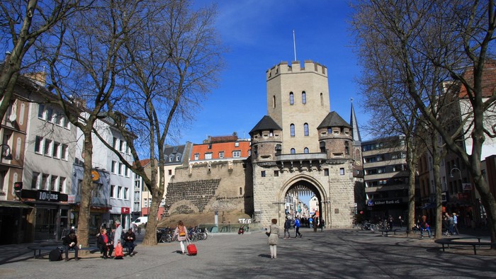 Historisches Stadttor mit Menschen und Bäumen im Vordergrund