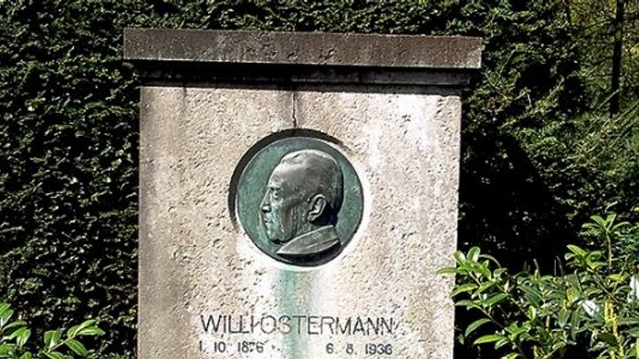 Grabstein mit Porträtmedaillon und Inschrift im Wald