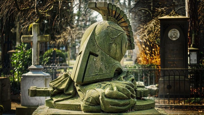 Das Bild zeigt eine grüne Soldatenstatue auf einem Friedhof.