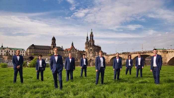 Ein Gruppe von Männern in Anzügen posiert vor einer historischen Burg.