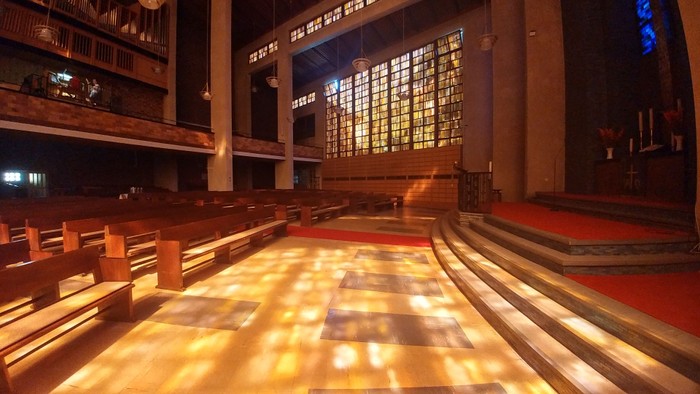 Die Kirche mit Holzpulten und farbigem Glasfenster