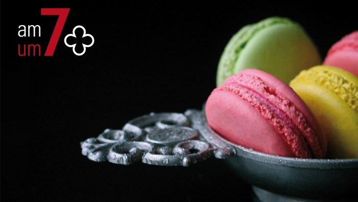 Bunte Macarons in silberner Schale auf schwarzem Hintergrund