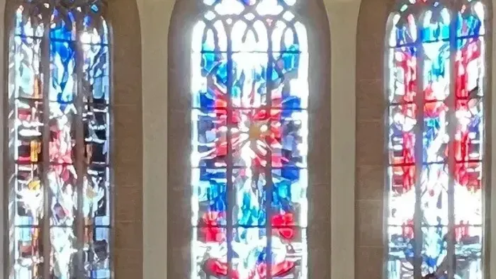 Drei Buntglasfenster mit filigranen Mustern und leuchtenden Farben.