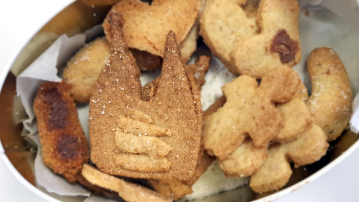 Ein Teller mit verschiedenen Keksformen, darunter Herzen und Streifen, auf weißem Papier.