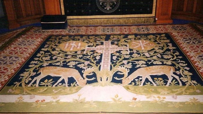 Billedet viser en smuk tæppe med dyr og blomster i en kirke.