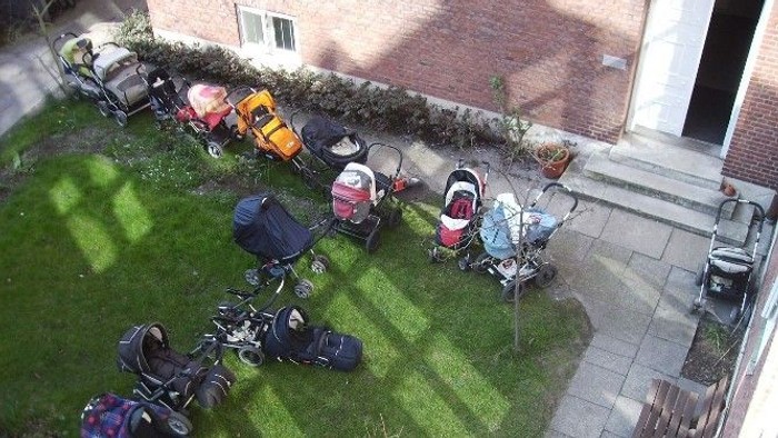 Mehrere Motorräder und Roller auf einem gepflasterten Hof vor einem Backsteingebäude.