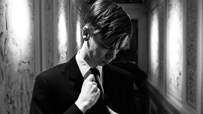 Mand justerer sit kragebånd i et historisk lokal.