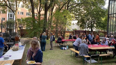 Im Freiluftrestaurant sitzen Menschen an Tischen, essen und unterhalten sich.