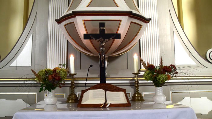 Blumengeschmückter Altartisch in Zossen mit Aktarkreuz und aufgeschlagenem Lektionar.