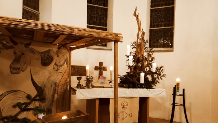 In der Kirche steht ein Tisch mit Kreuz, Kerzen und Weihnachtsdekoration.