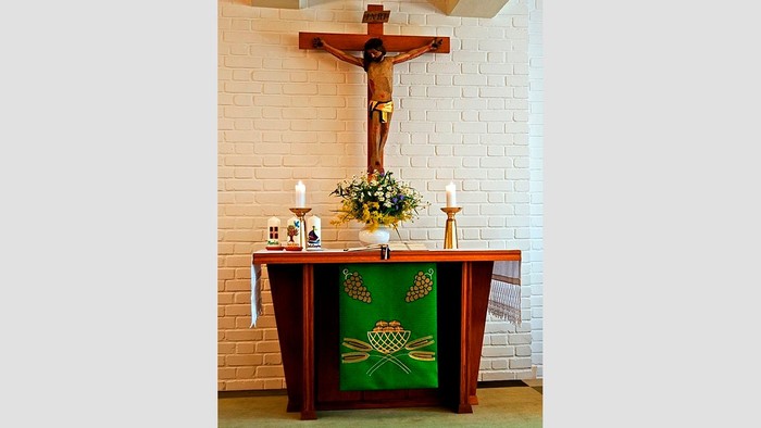 Ein Altar mit Kreuz, Kerzen und Blumen in einer Kirche