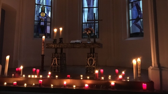 Kirchliche Innenansicht mit brennenden Kerzen und farbenfrohen Buntglasfenstern