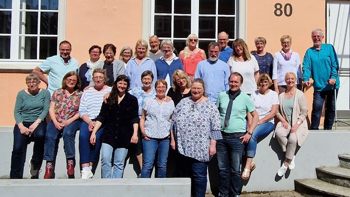 Eine Gruppe von Menschen posiert vor einem Gebäude mit der Nummer 80.