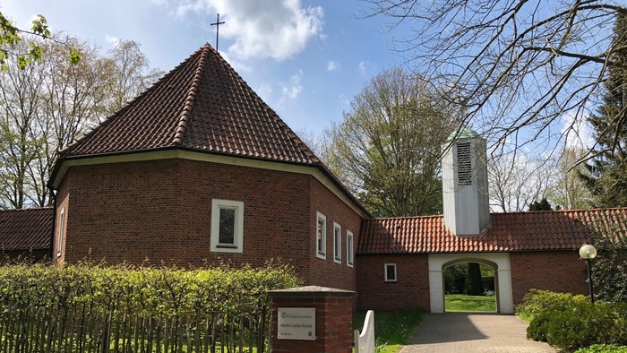 Kirchliche Anlage mit rotem Backsteingebäude und weißem Glockenturm im Hintergrund
