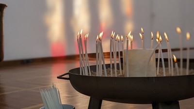 Mehrere brennende Kerzen in einem Halter in einem Gebäude.