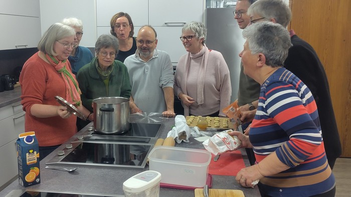 Eine Gruppe von Menschen bereitet in einer Küche gemeinsam ein Essen zu.