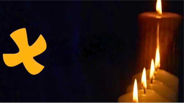 Ein gelbes Symbol und brennende Kerzen vor dunklem Hintergrund