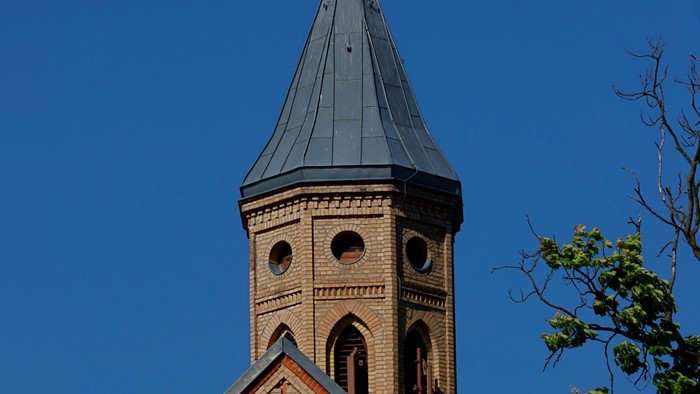 Kirchturm mit Kreuz vor blauem Himmel