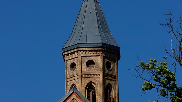 Kirchturm mit Kreuz vor blauem Himmel