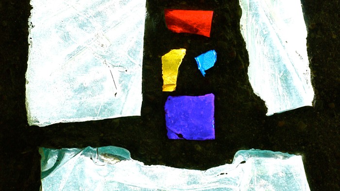 Vier zerknitterte Papierstücke in verschiedenen Größen und Farben auf schwarzem Hintergrund