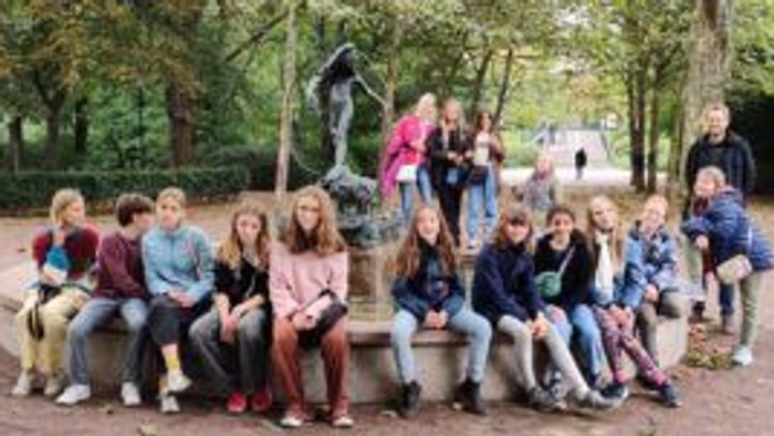 Eine Gruppe von Menschen sitzt auf einer Bank im Park und posiert für ein Foto.