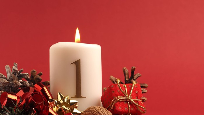 En lysende adventstæppe med tallet 1 omgivet af juleriger og nødder på rød baggrund